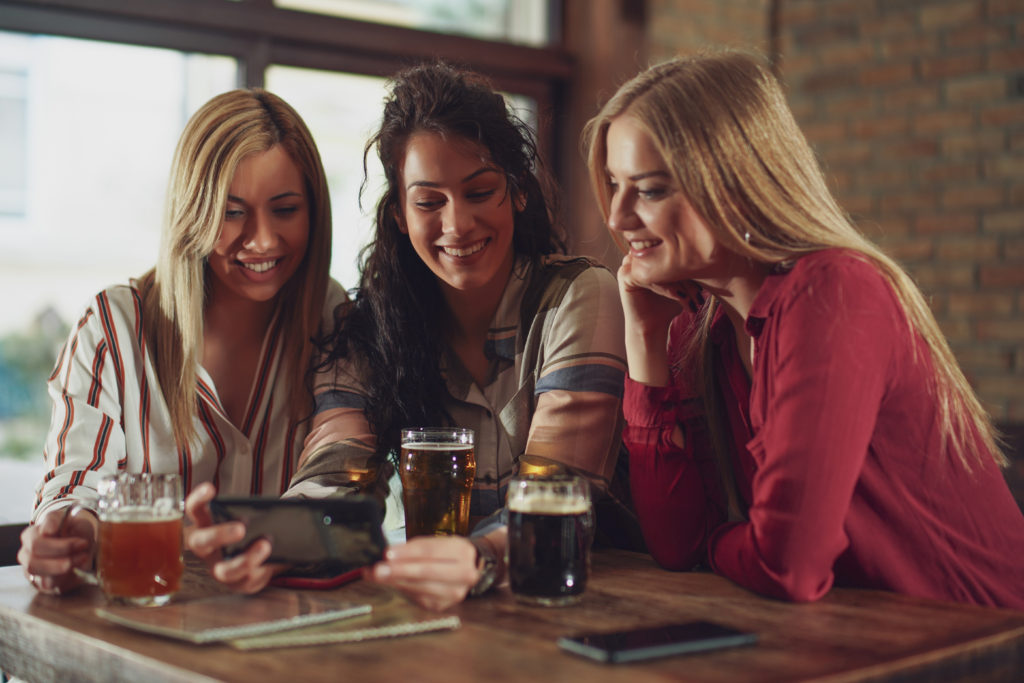 Female friends at a bar playing trivia and smiling.