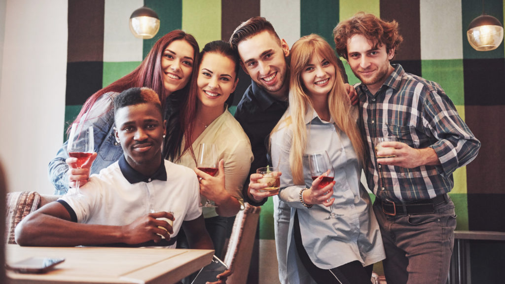 Multiracial people having fun at cafe taking a selfie with mobile phone. Group of young friends sitting at restaurant.