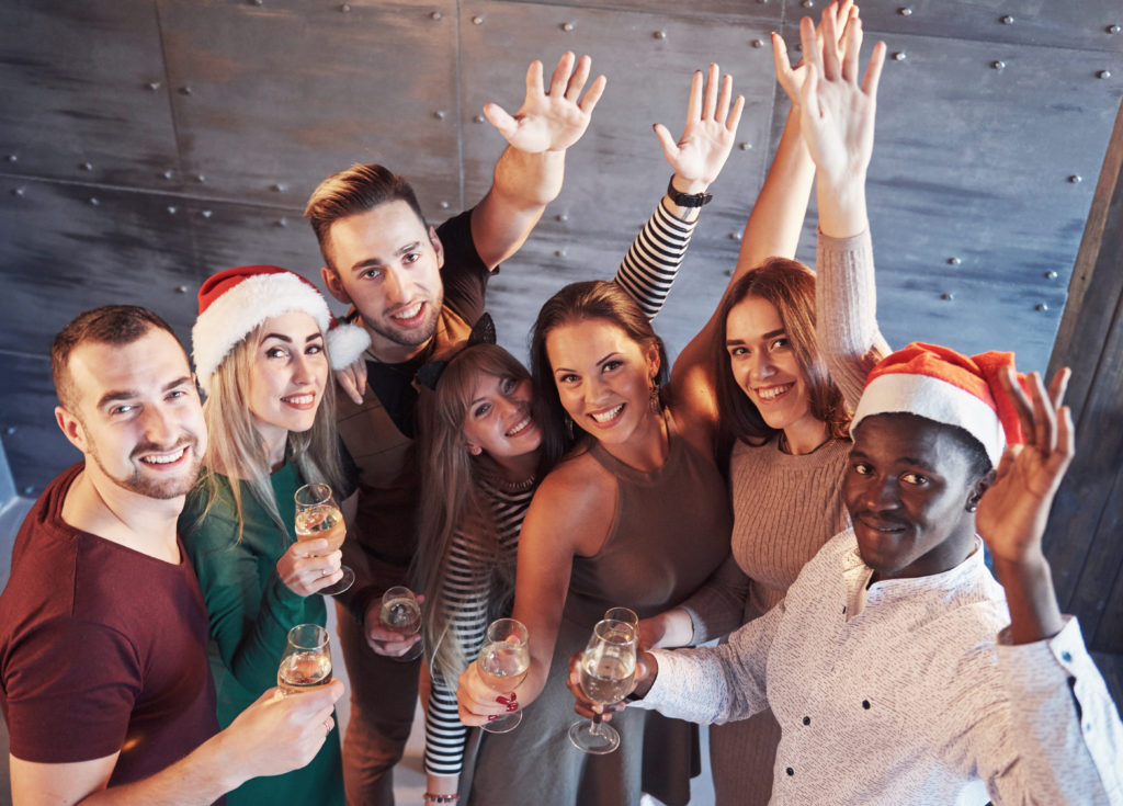 Group of cheerful young multiethnic people in Santa hats on the party, posing emotional lifestyle people concept.